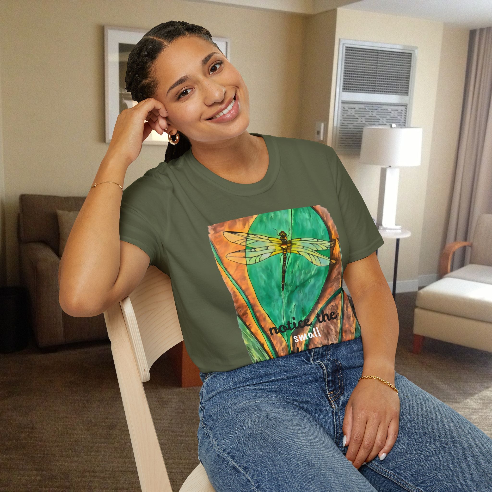 Woman wearing a green t-shirt with a dragonfly design in a room.