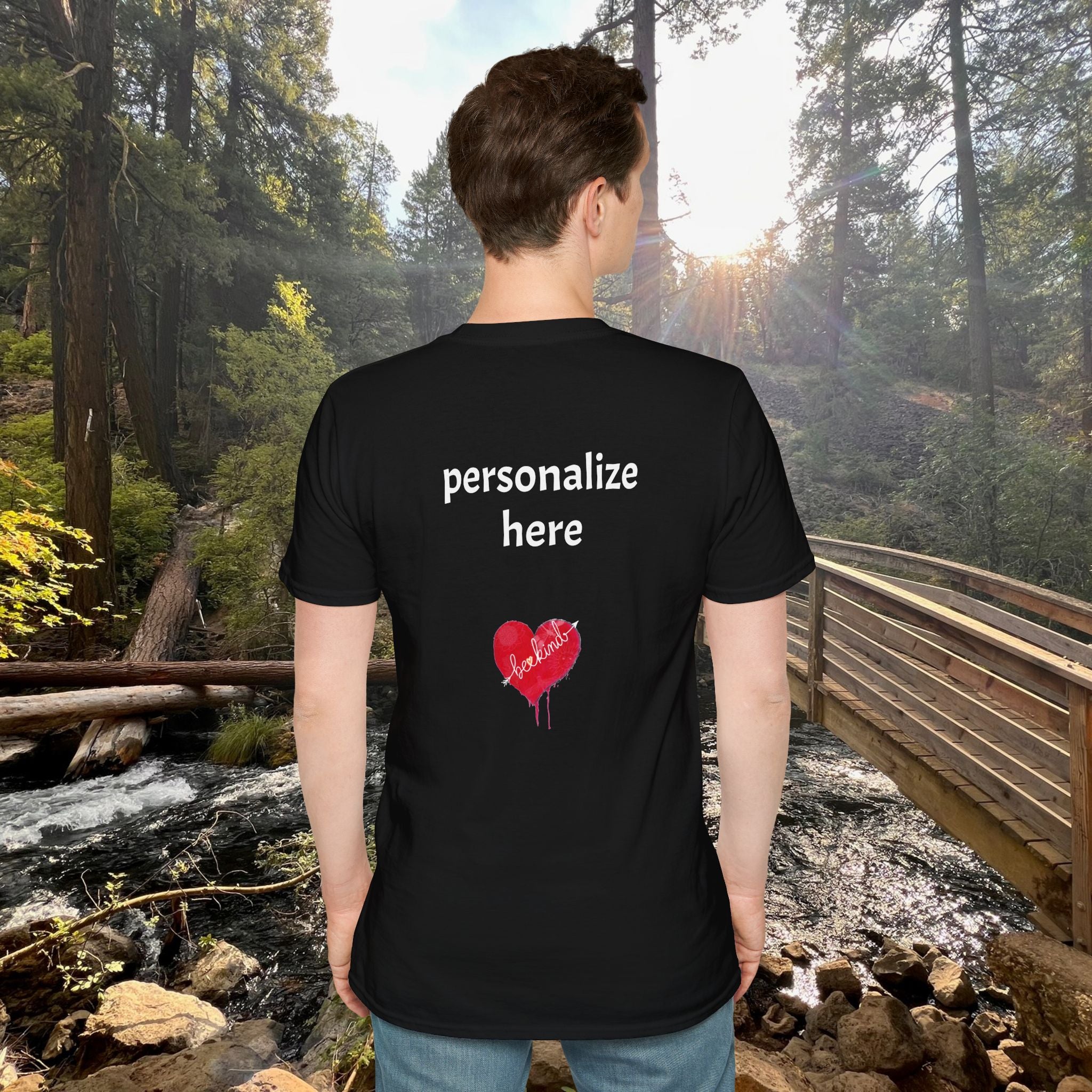 Person wearing a black t-shirt with text and a heart design in a forest setting