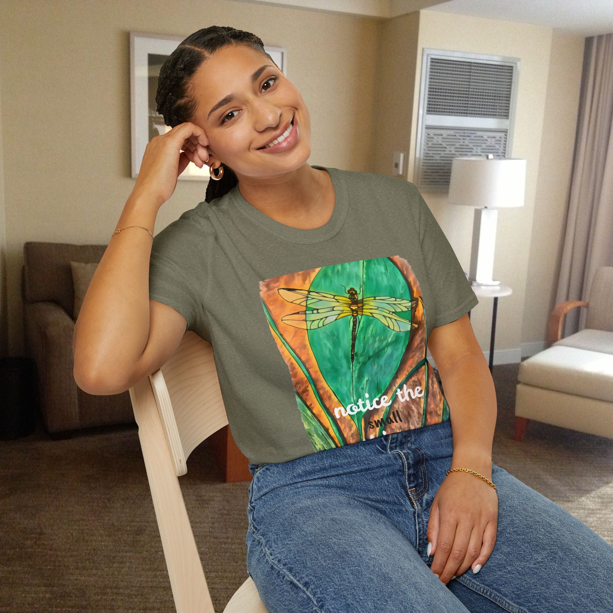 Woman wearing a graphic t-shirt with a dragonfly design in a room.