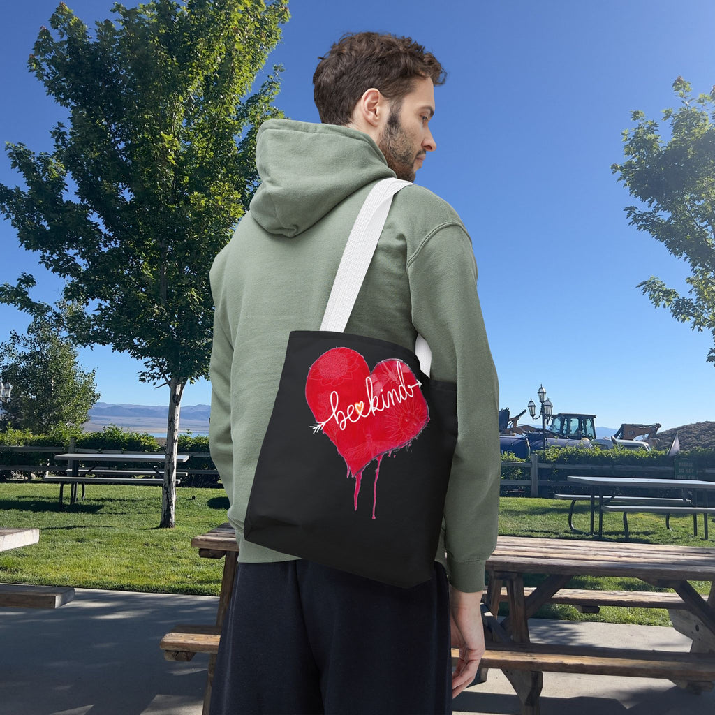 Person wearing a green hoodie with a black bag featuring a red heart design outdoors.
