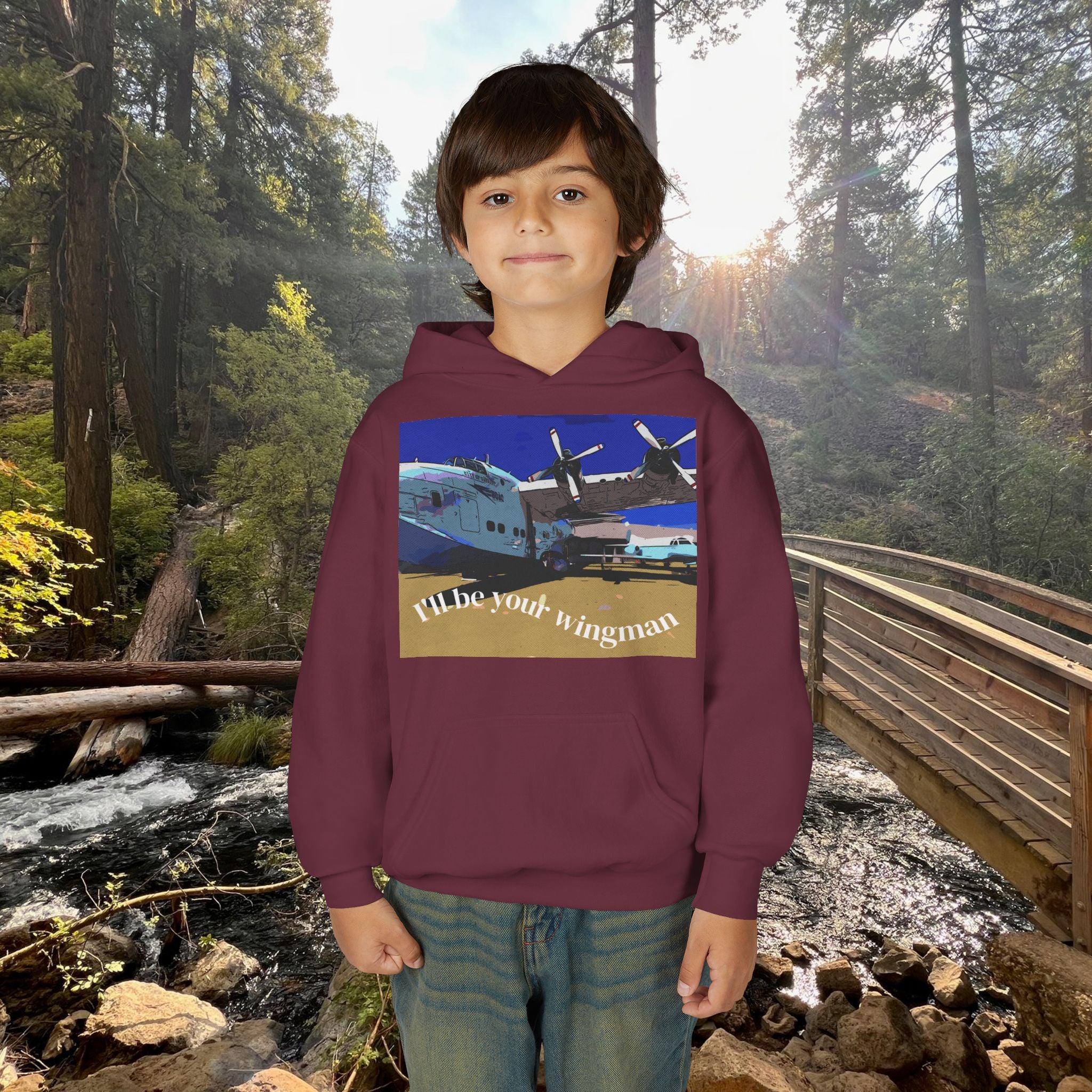 Child wearing a hoodie with an airplane graphic and text in a forest setting