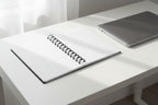 Open spiral bound notebook with laptop next to it on a desk