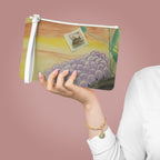 Hand holding a pouch with a painting of grapes and a postcard on a pink background