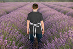 Person wearing a black apron over a gray shirt in a lavender garden
