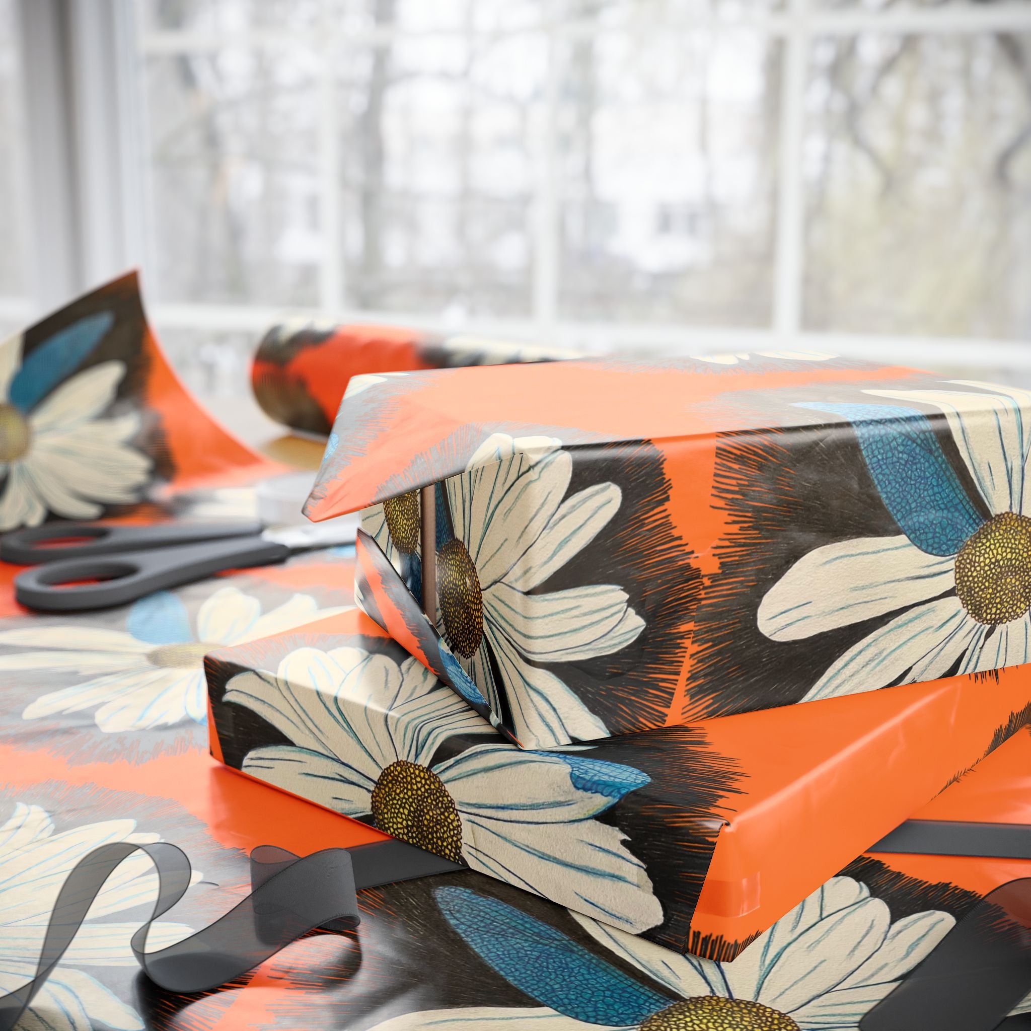 Gift box with floral design on a table with scissors and ribbons.