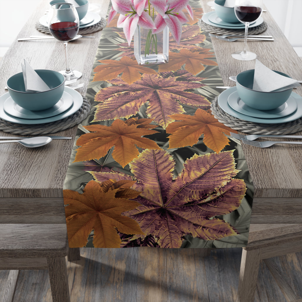 Table setting with a leaf-patterned table runner on a wooden table.
