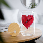 Clear glass tumbler with red heart and 'be kind' text on a wooden table.