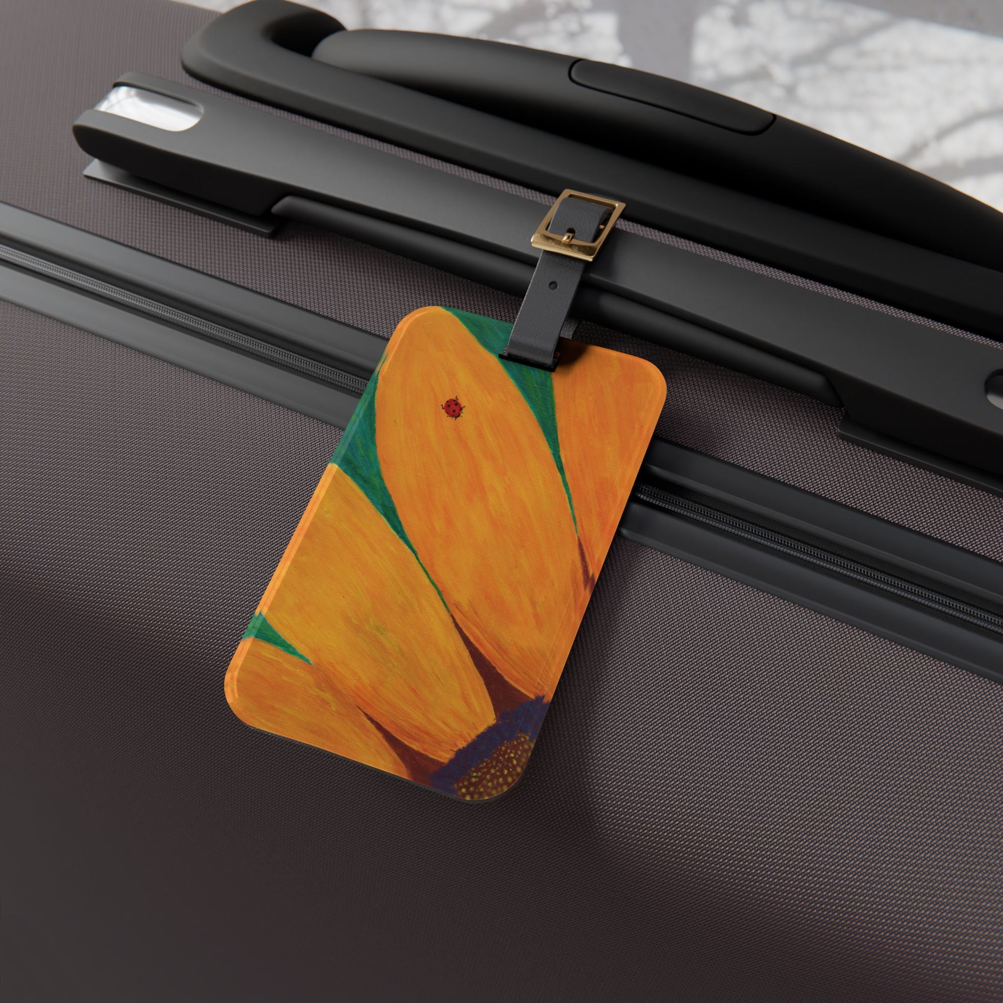Luggage tag with ladybug on a sunflower petal design attached to a suitcase
