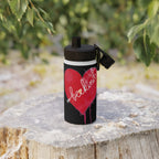 Black water bottle with red heart design and 'beckin' text on a wooden stump with greenery in the background