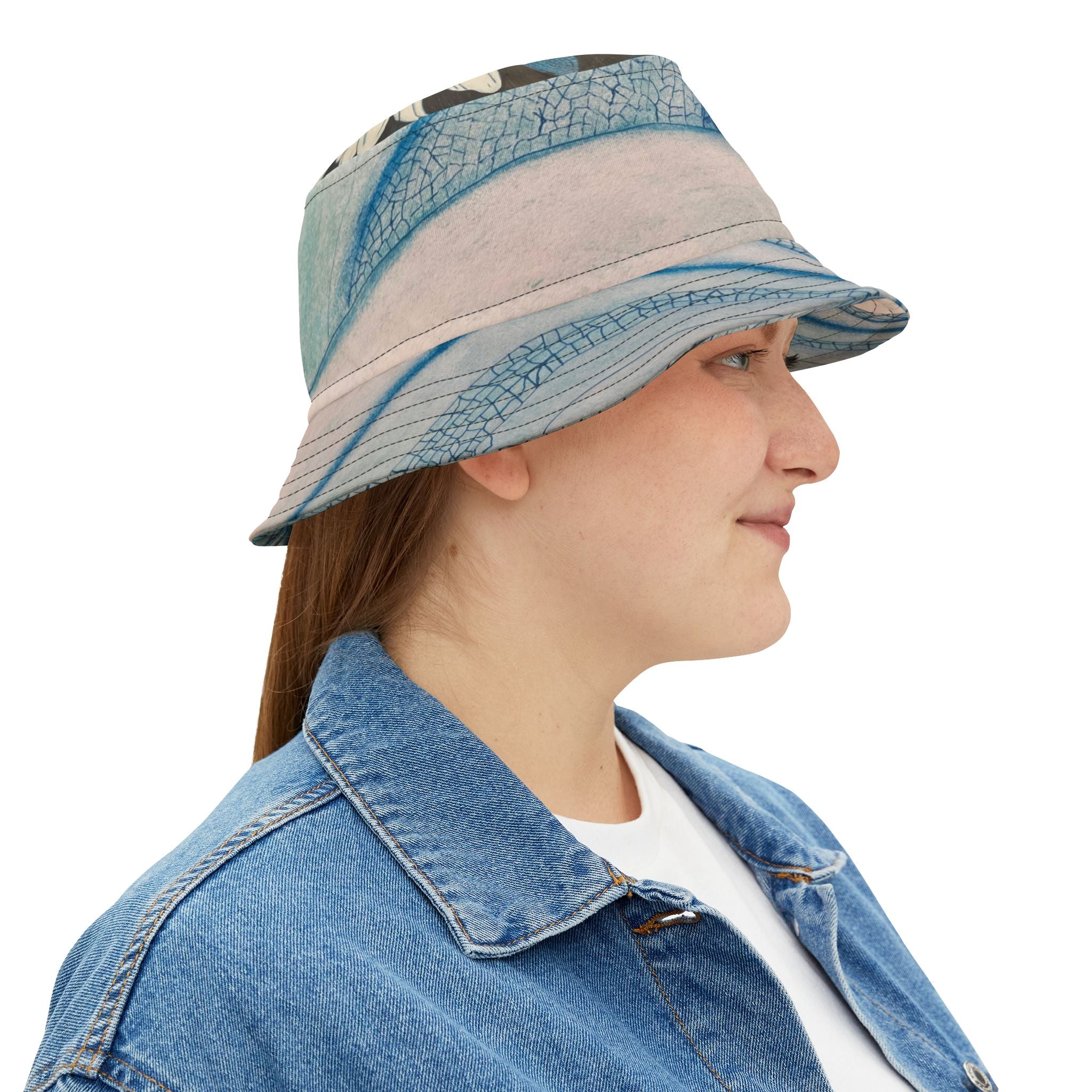 Person wearing a blue and beige bucket hat with a denim jacket on a white background