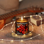 Candle with pumpkin design on a wooden coaster surrounded by string lights, with a guitar in the background.