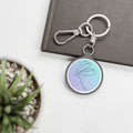 Keychain with a butterfly design on a white surface with a plant and book in the background