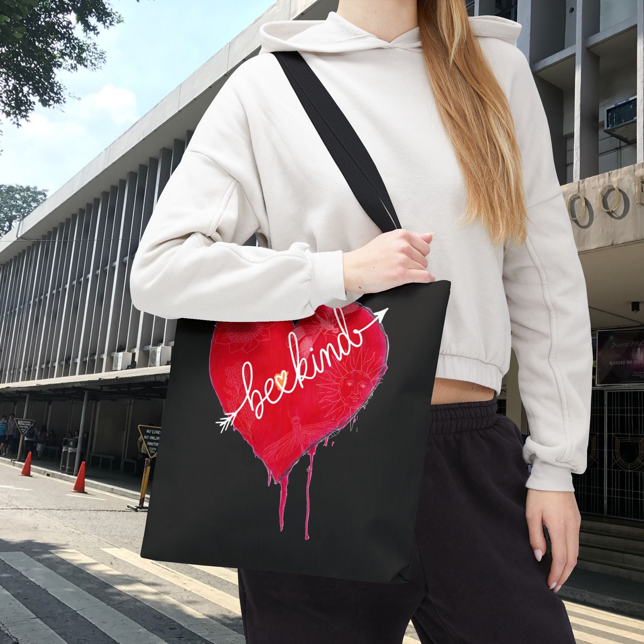 Person holding a black tote bag with a red heart design and 'beckin' logo.