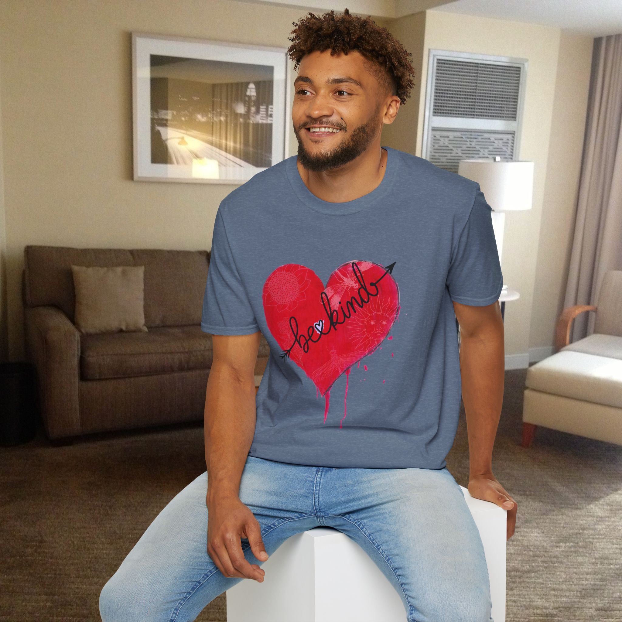 Man wearing a blue t-shirt with a red heart design sitting in a living room.
