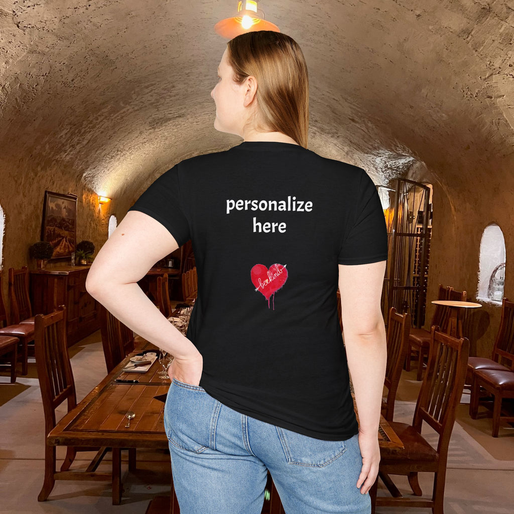 Person wearing a black t-shirt with text and a heart design in an indoor setting.