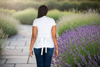 Woman wearing a white wrap dress over a white shirt with blue jeans in a lavender garden