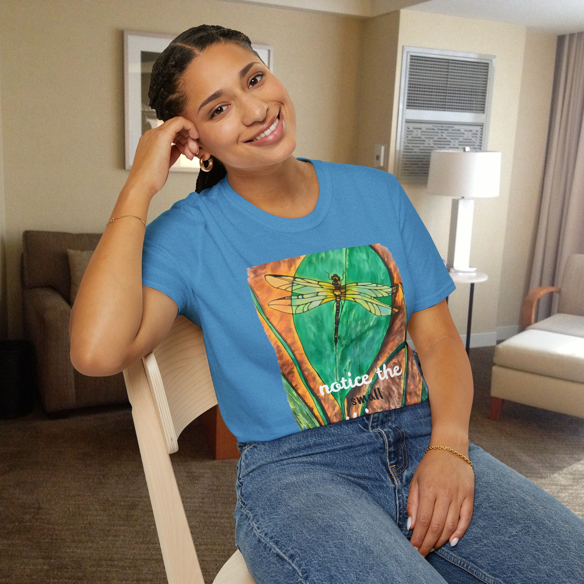 Woman wearing a blue t-shirt with a dragonfly design in a room.