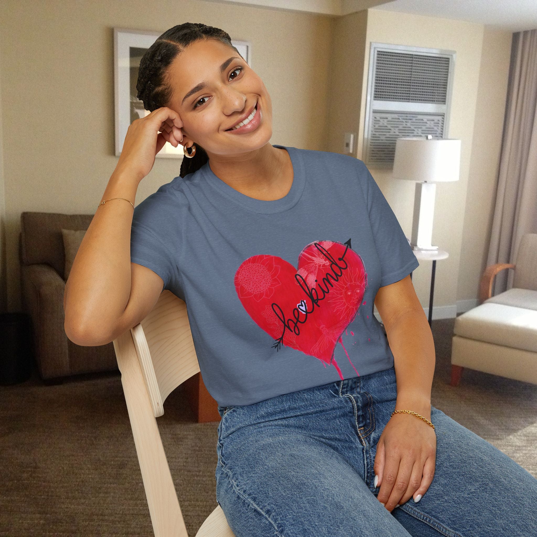Woman wearing a blue t-shirt with a red heart design sitting in a room.