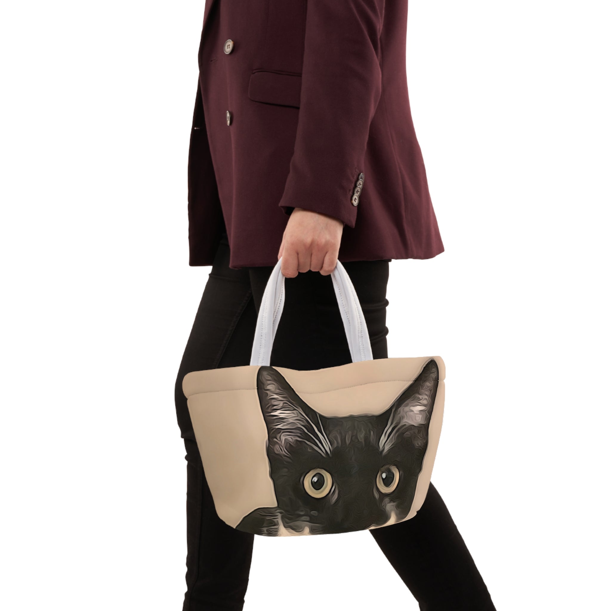 Person holding a handbag with a cat design on a white background