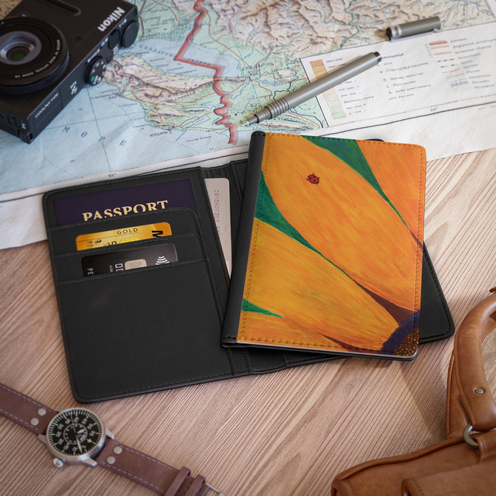 Passport, wallet, camera, map, pen, and watch on a wooden surface