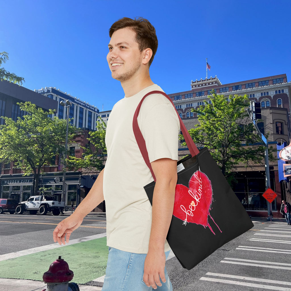 Man holding a black tote bag with a red heart design in an urban setting