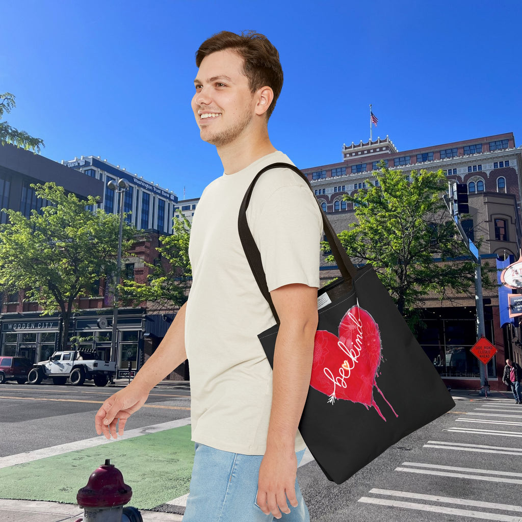 Man walking outdoors with a black tote bag featuring a red heart design.