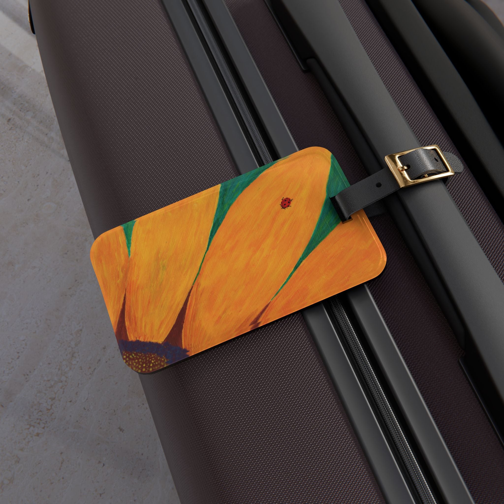 Luggage tag with ladybug on a sunflower design attached to a suitcase