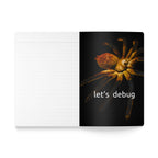 Notebook with a spider illustration and 'let's debug' text on a black cover