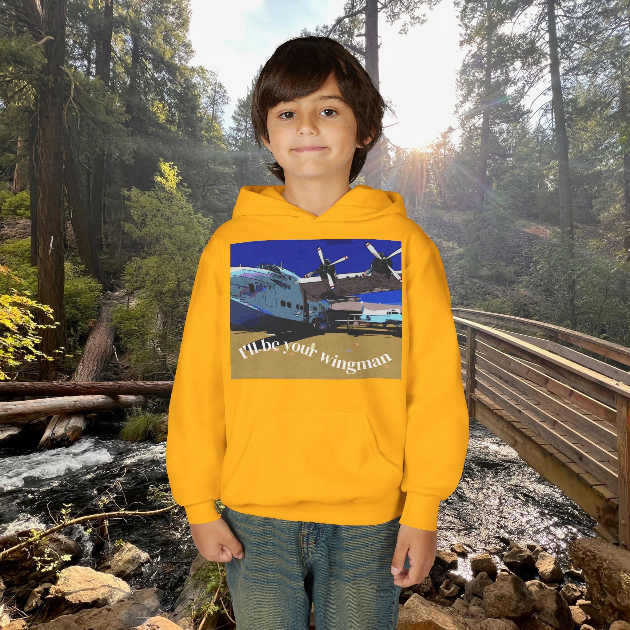 Child wearing a yellow hoodie with a graphic design in a forest setting