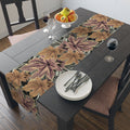 Dining table set with a leaf-patterned table runner, plates, and glasses.