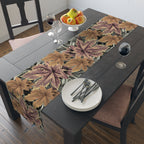 Dining table set with a leaf-patterned table runner, plates, and glasses.