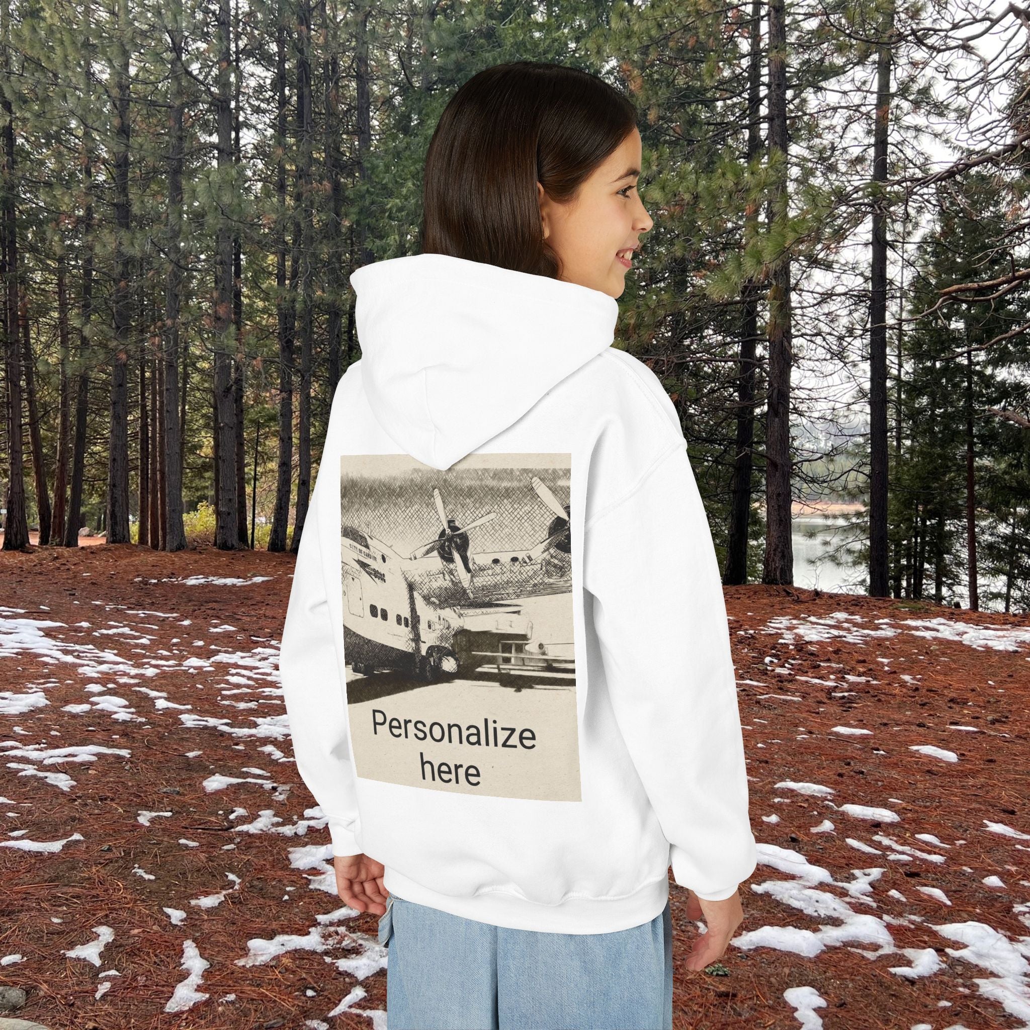 Person wearing a white hoodie with a printed design in a forest setting