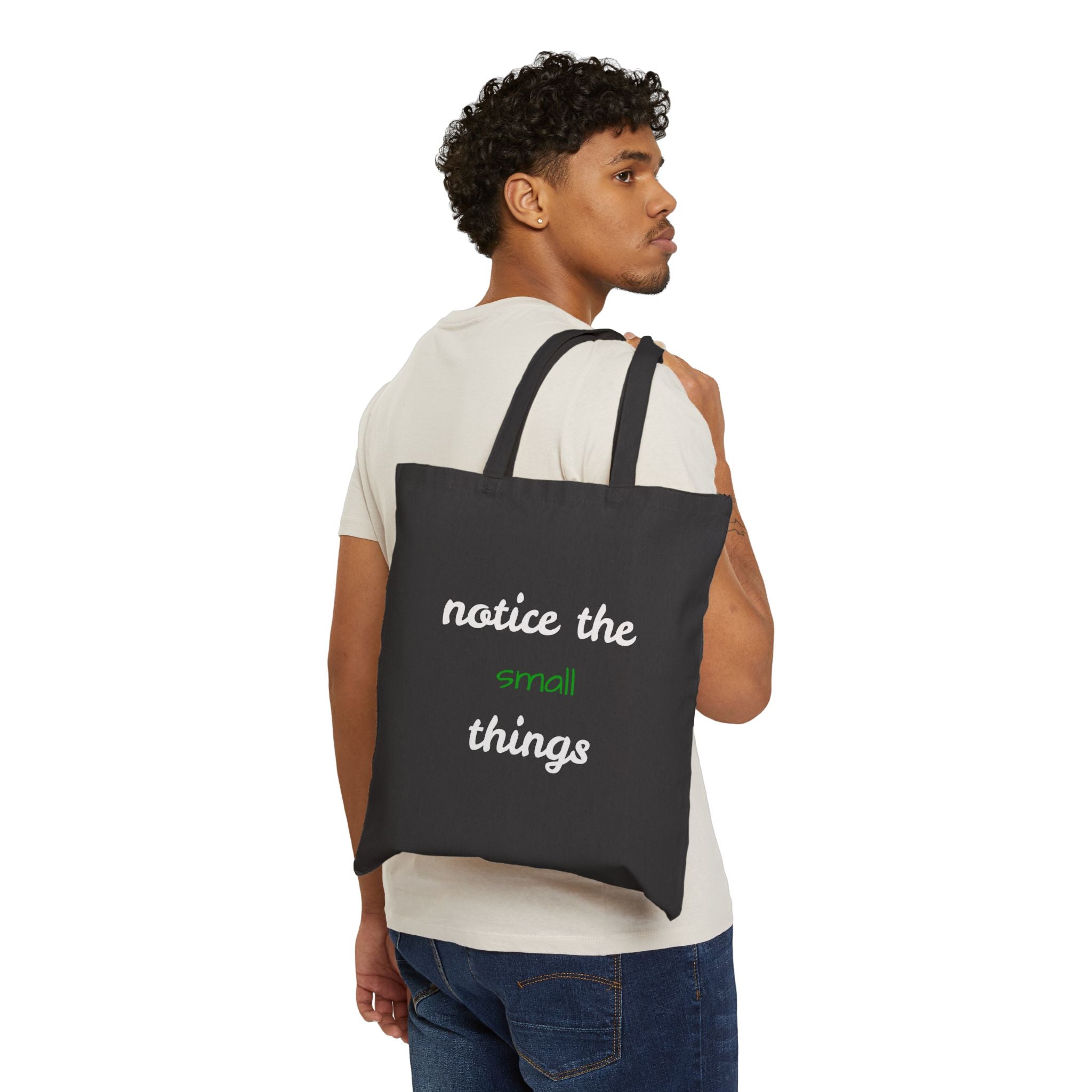 Man carrying a black tote bag with 'notice the small things' text on a white background