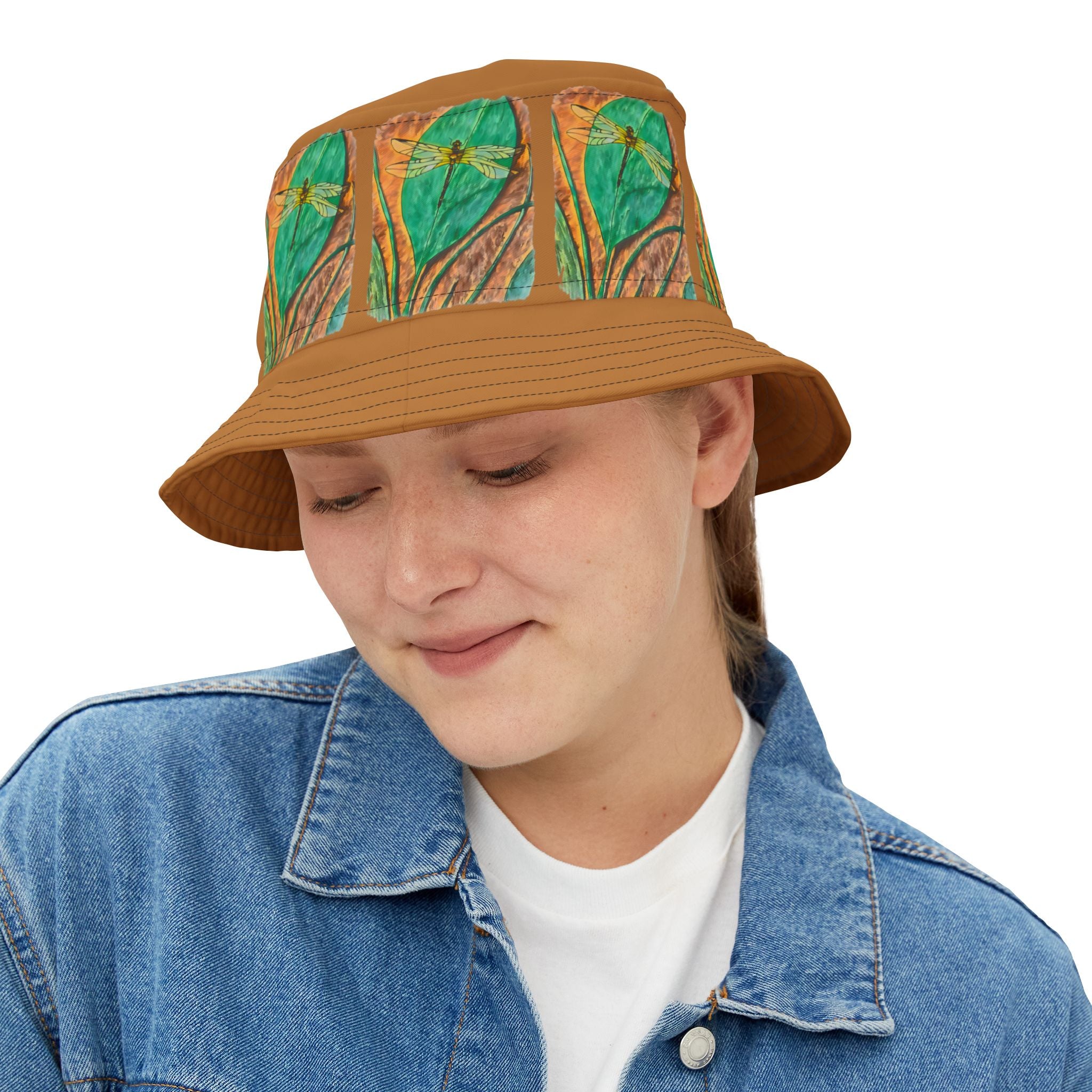 Person wearing a brown bucket hat with dragonfly on a leaf pattern on a white background