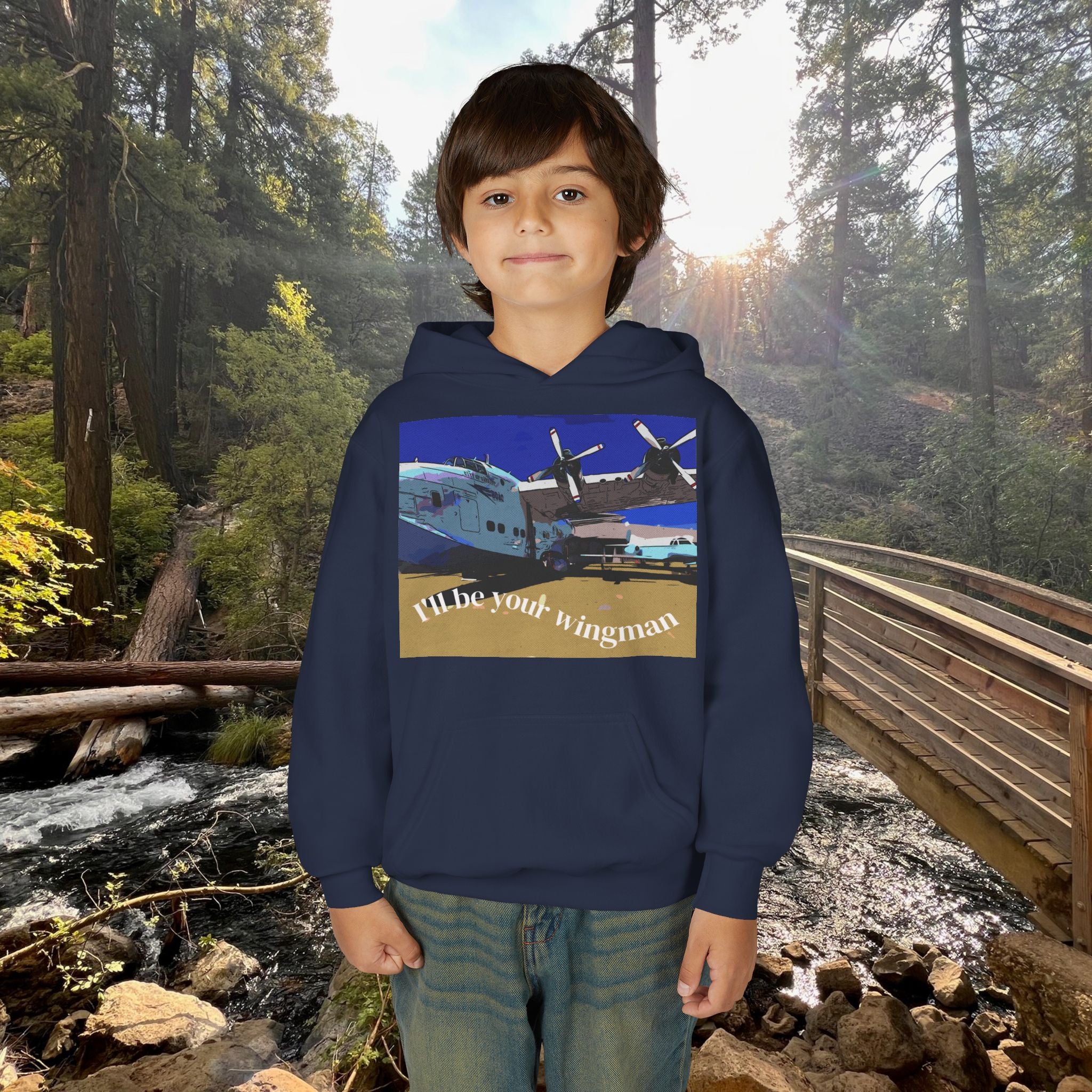 Child wearing a hoodie with an airplane graphic and text in a forest setting