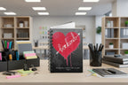 Spiral bound notebook with a bleeding red heart design with be kind text on an office supply area background