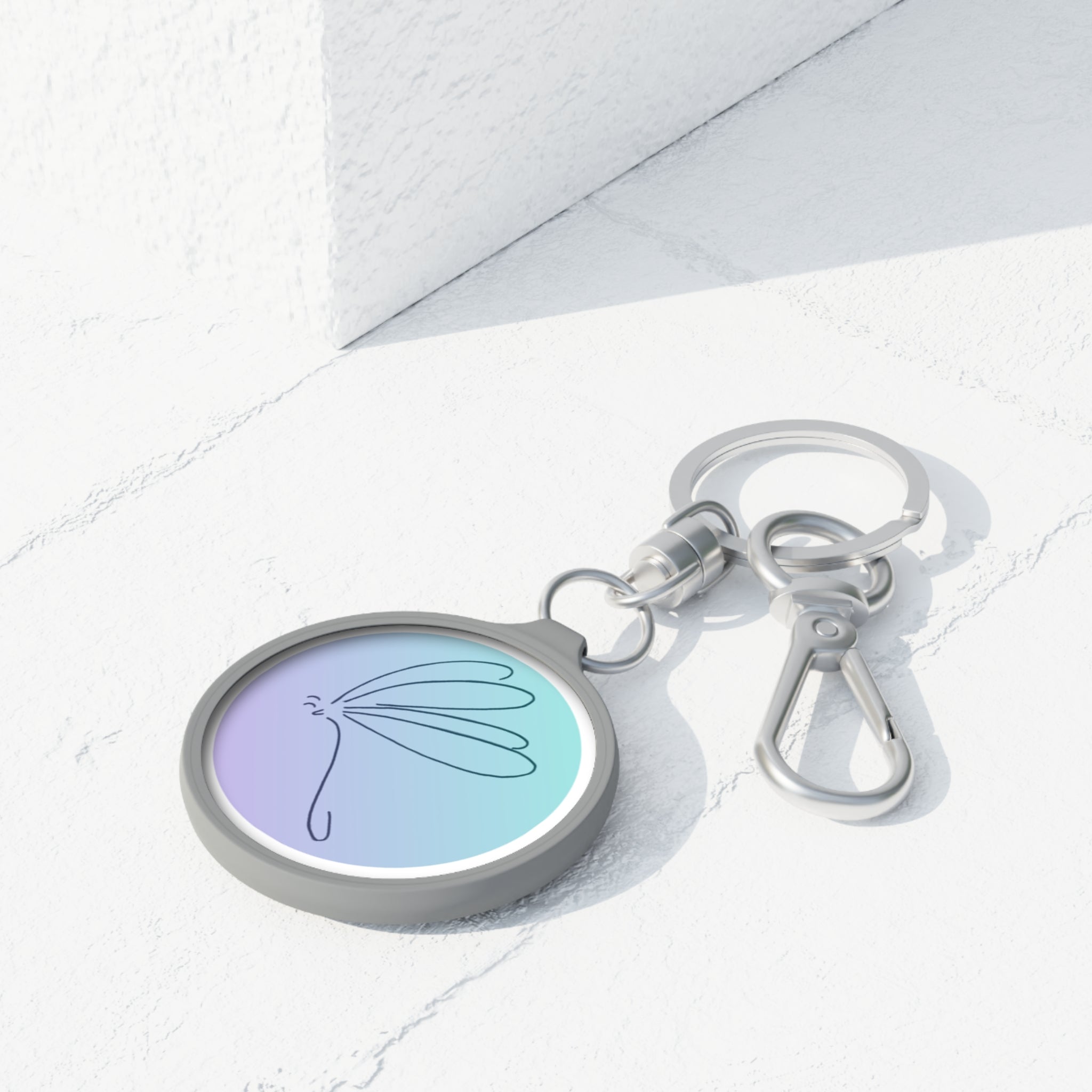 Keychain with a pastel-colored circular charm featuring a butterfly design on a white surface.