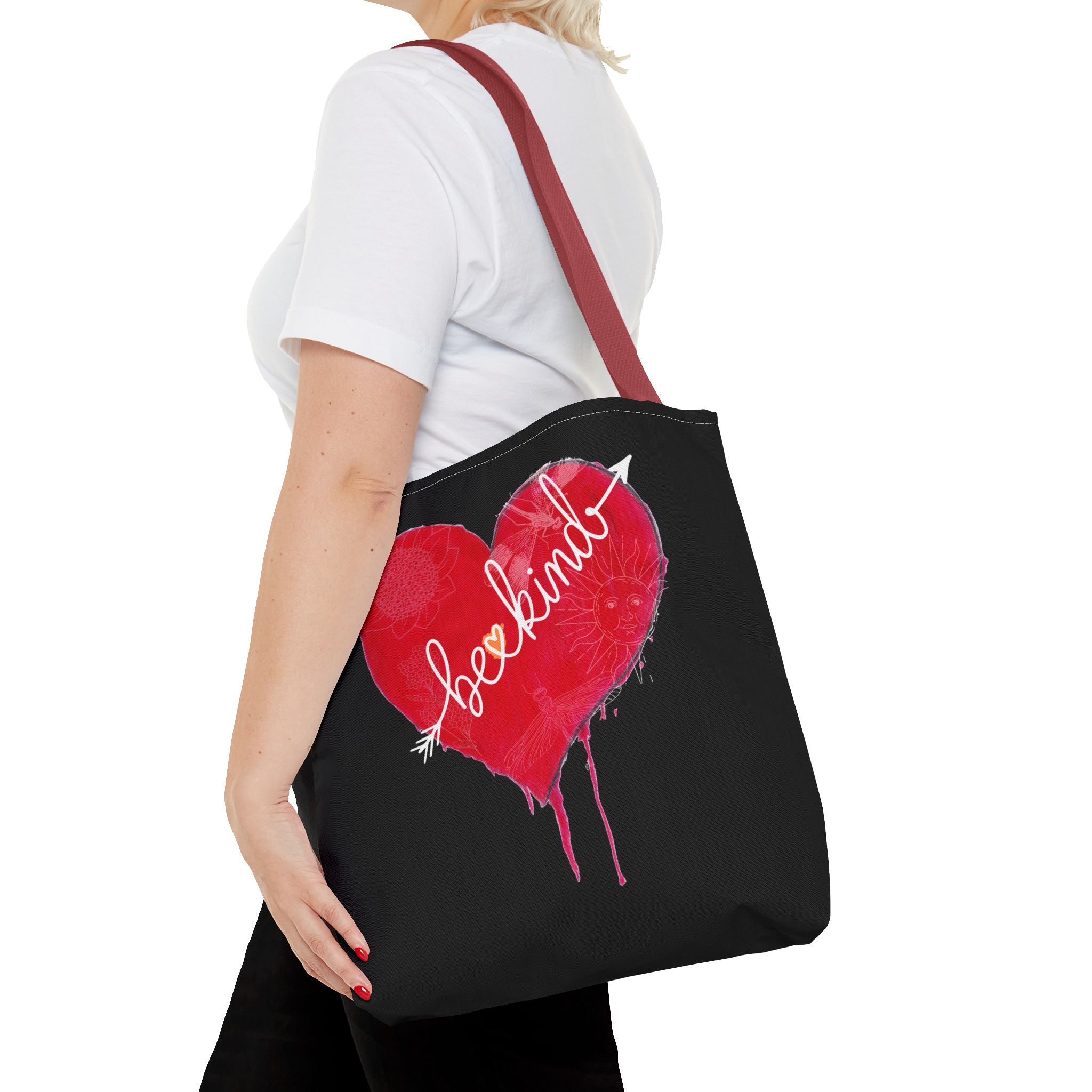 Person holding a black tote bag with a red heart design and 'loekind' text.