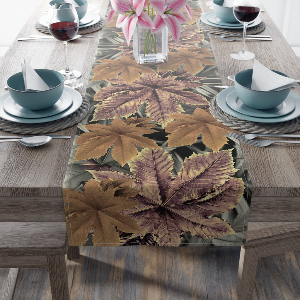 Table setting with a leaf-patterned table runner on a wooden table.