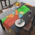 Colorful abstract table runner on a wooden table with fruit and wine glasses.
