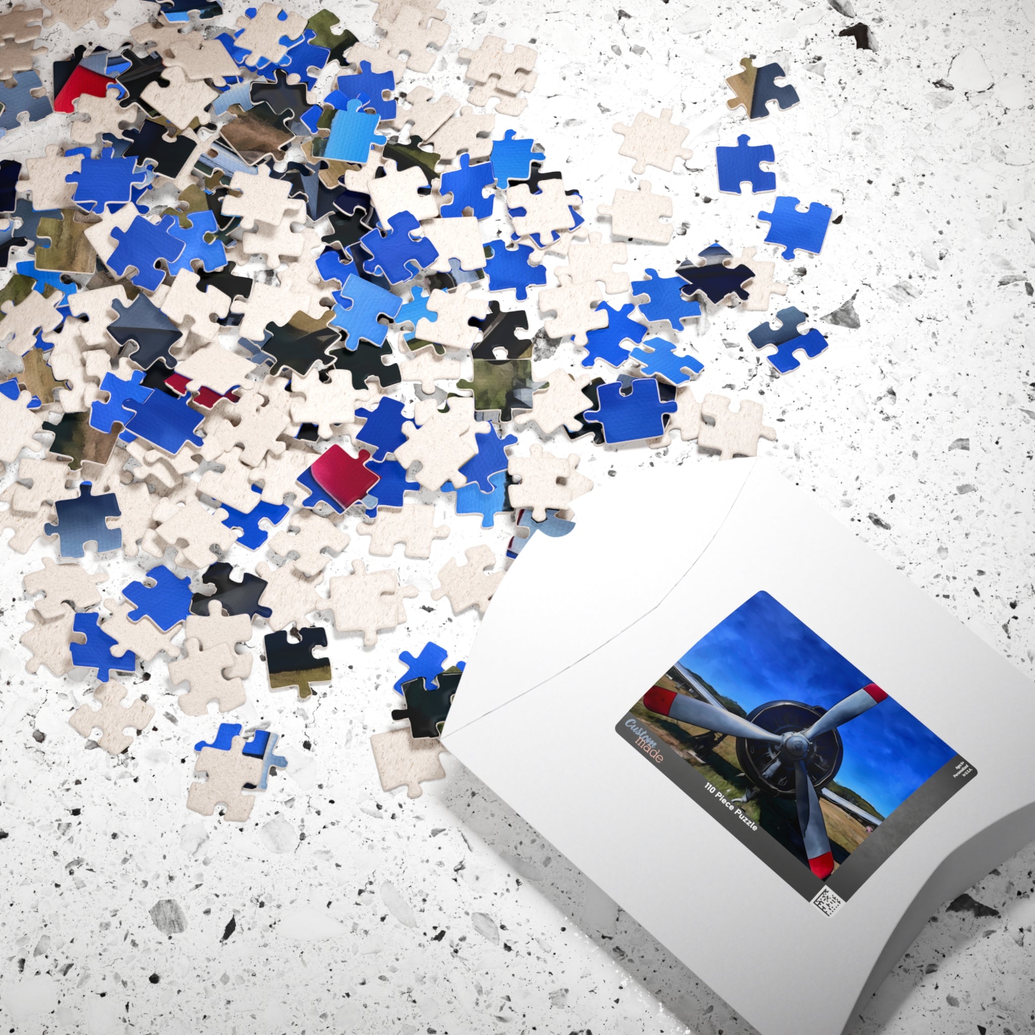 Jigsaw puzzle pieces on a surface with a completed puzzle showing an airplane propeller