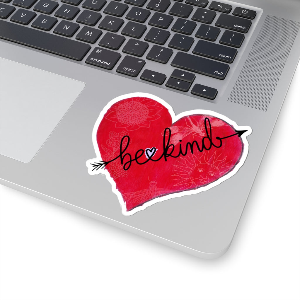 Laptop with a red heart-shaped sticker that says 'be kind' on the palm rest area.