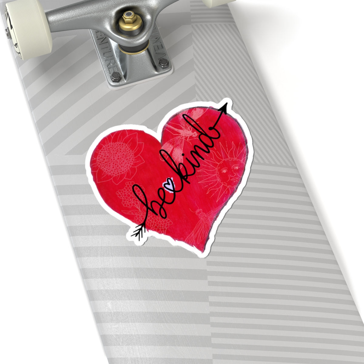 Red heart-shaped sticker with 'be kind' text on a skateboard deck