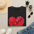 Black t-shirt with red hearts and 'be kind' text on a light surface with accessories.