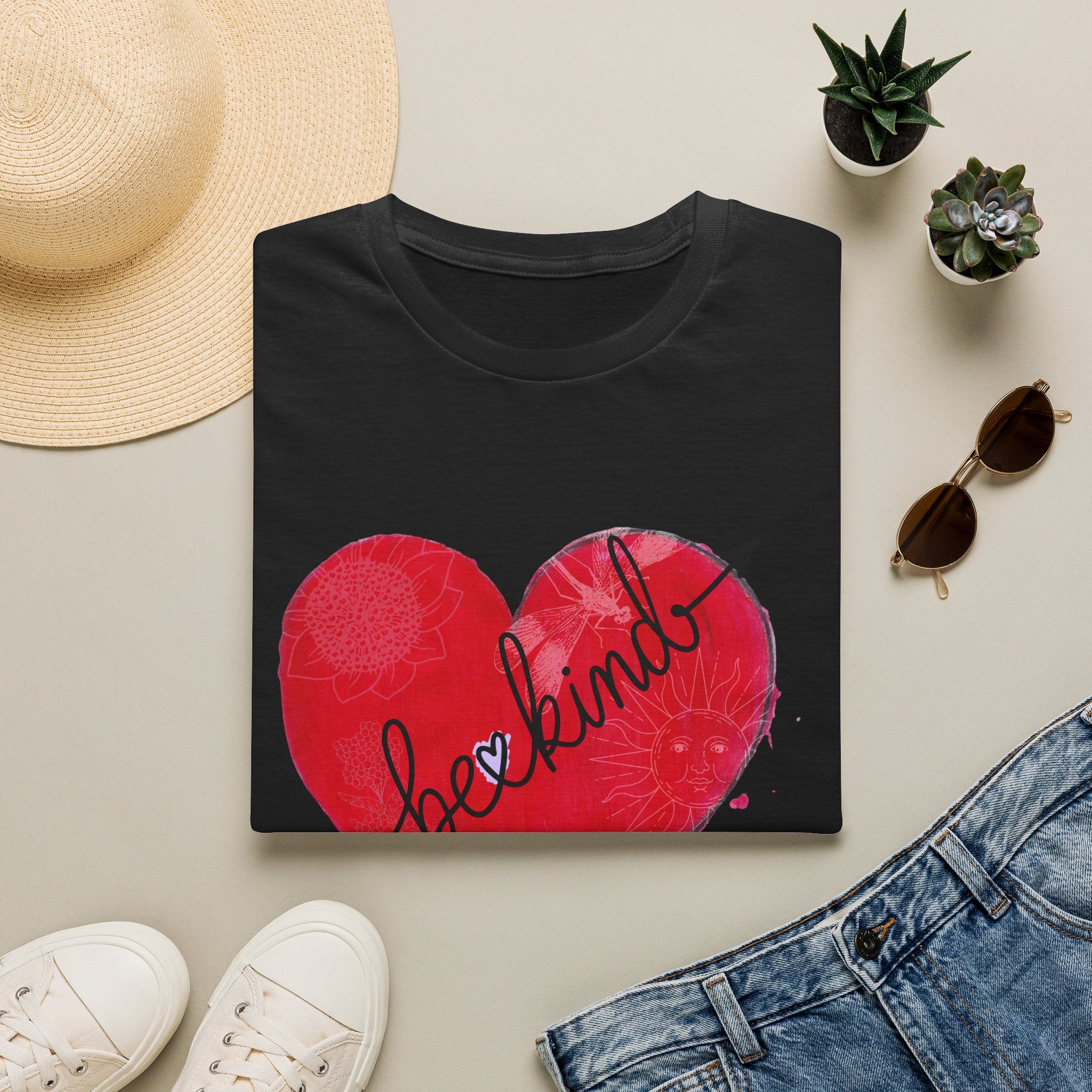 Black t-shirt with red hearts and 'be kind' text on a light surface with accessories.
