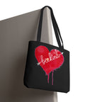 Black tote bag with a red heart and white text hanging on a grey cubicle wall