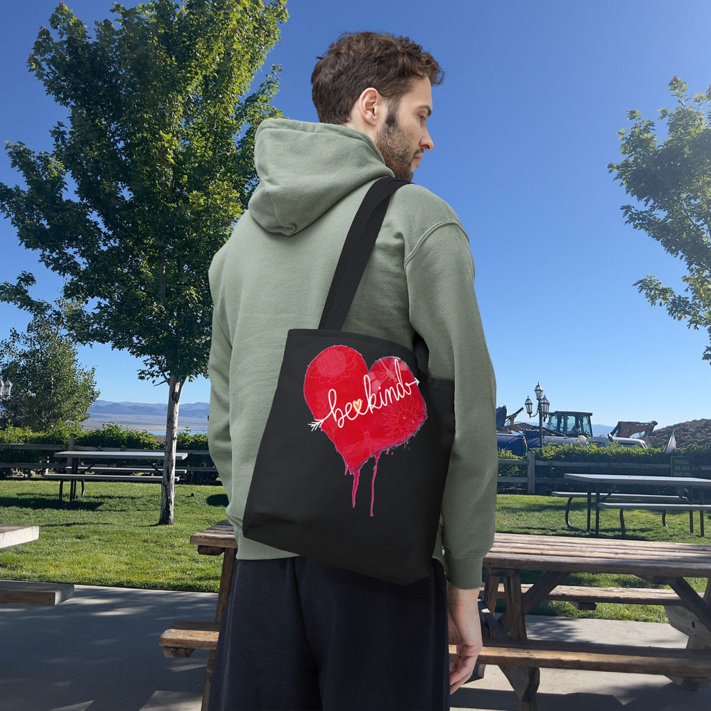 Man wearing a green hoodie with a black bag featuring a red heart design outdoors.