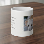 A white ceramic mug featuring a printed design with black text on the left and a square photo of a light-colored dog on the right, shown against a dark wood kitchen counter