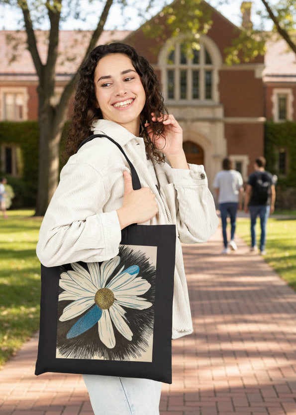 Woman holding a tote bag with a Daisy Dragonfly Wings petals design at a college setting