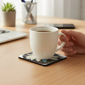 Daisy Dragonfly Wings Peters Coaster with a hand holding a coffee cup on a desk with laptop, succulent plant, phone and pen holder